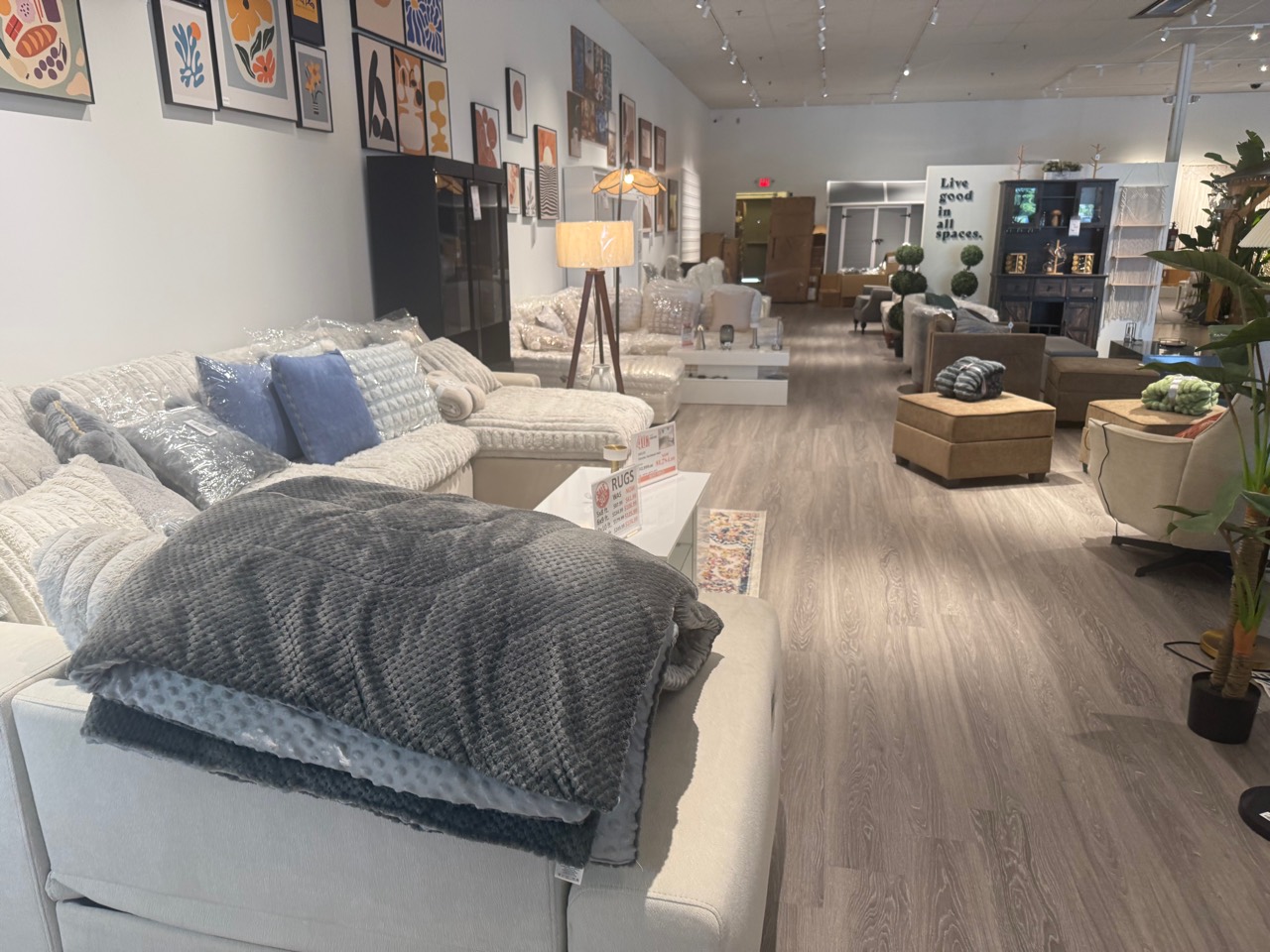 Living room showroom with blankets, pillows, and art